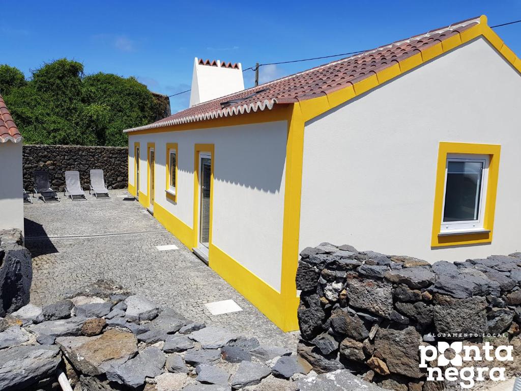 un edificio blanco y amarillo con una pared de piedra en Recanto das 5 en Cinco Ribeiras