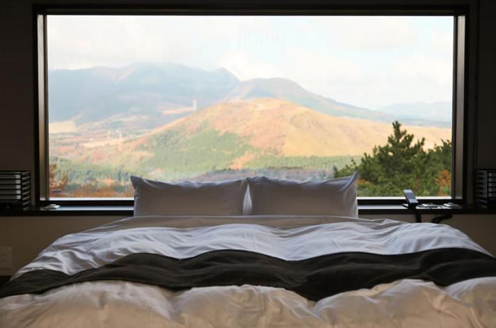 ein Bett mit einem großen Fenster mit Bergblick in der Unterkunft Okuyado Buaiso in Yufu