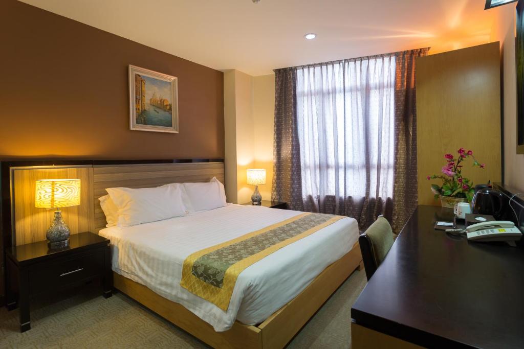 マラッカにあるホールマーク ビュー ホテルの大きなベッドとデスクが備わるホテルルームです。