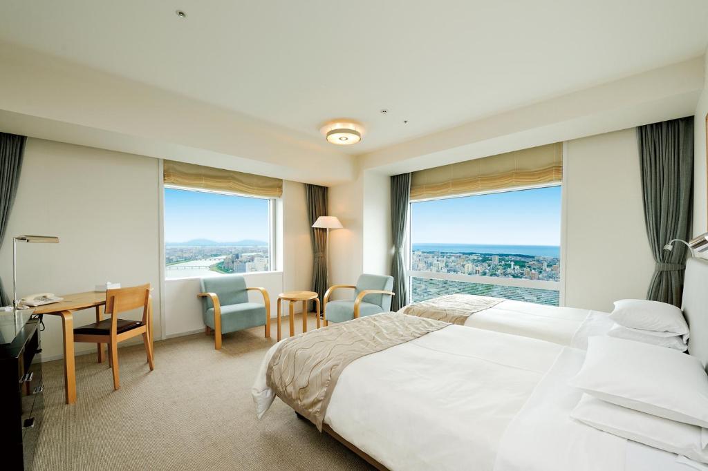 a hotel room with a bed and a desk and windows at Hotel Nikko Niigata in Niigata