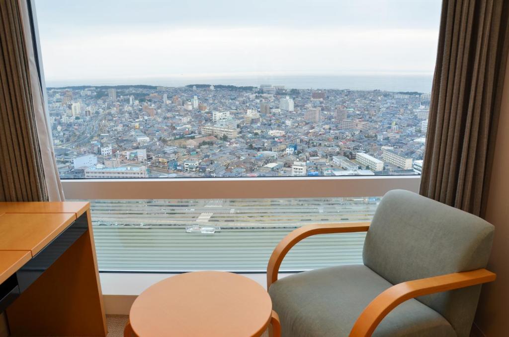 a room with a chair and a large window at Hotel Nikko Niigata in Niigata