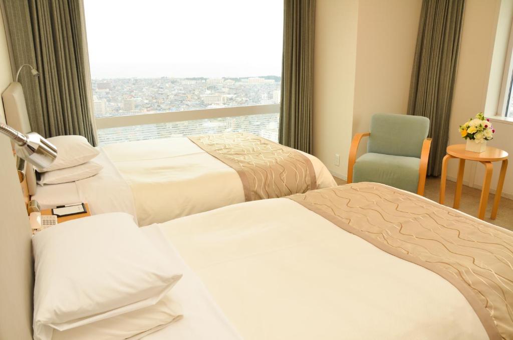 a hotel room with two beds and a window at Hotel Nikko Niigata in Niigata