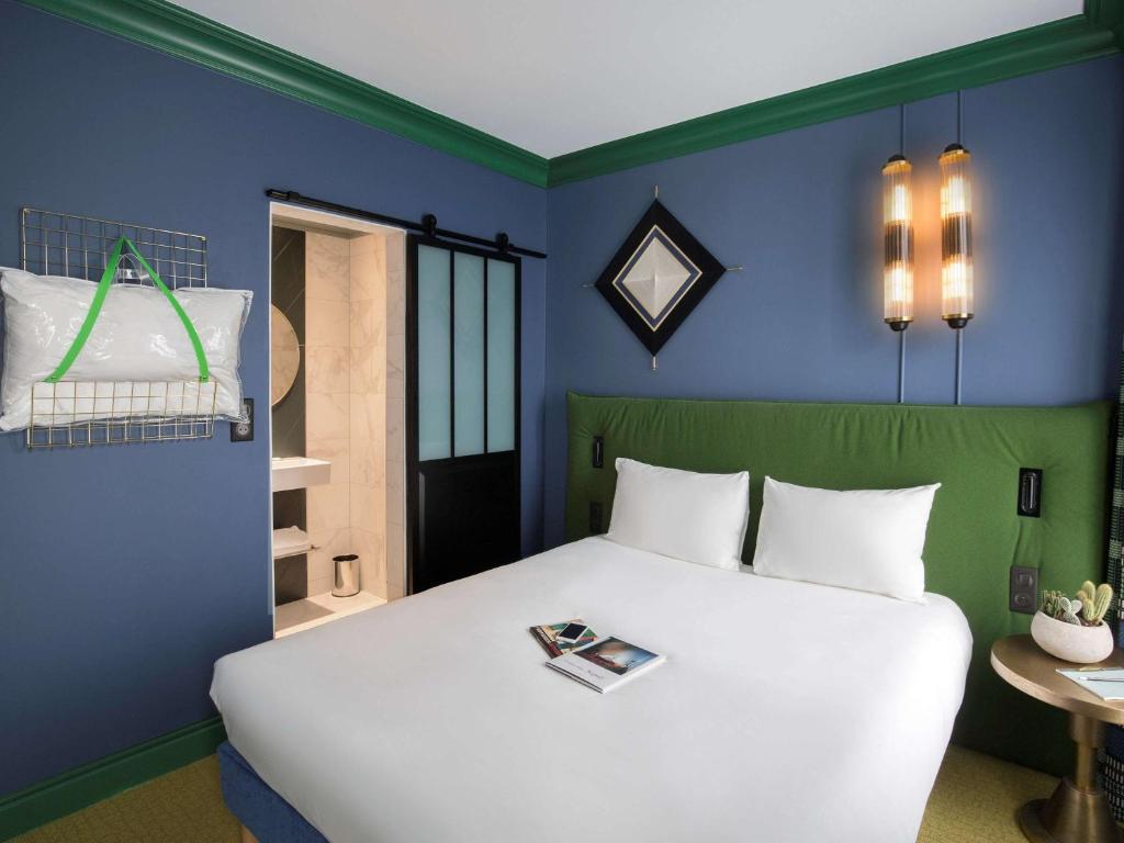 パリにあるイポテル パリ ナシヨン ガールドリヨンの白いベッドと青い壁が備わるベッドルーム1室が備わります。