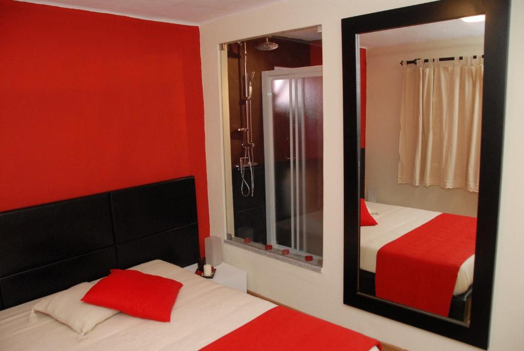1 dormitorio con paredes rojas, espejo y cama en SEIA Alojamento D Ines, en Seia