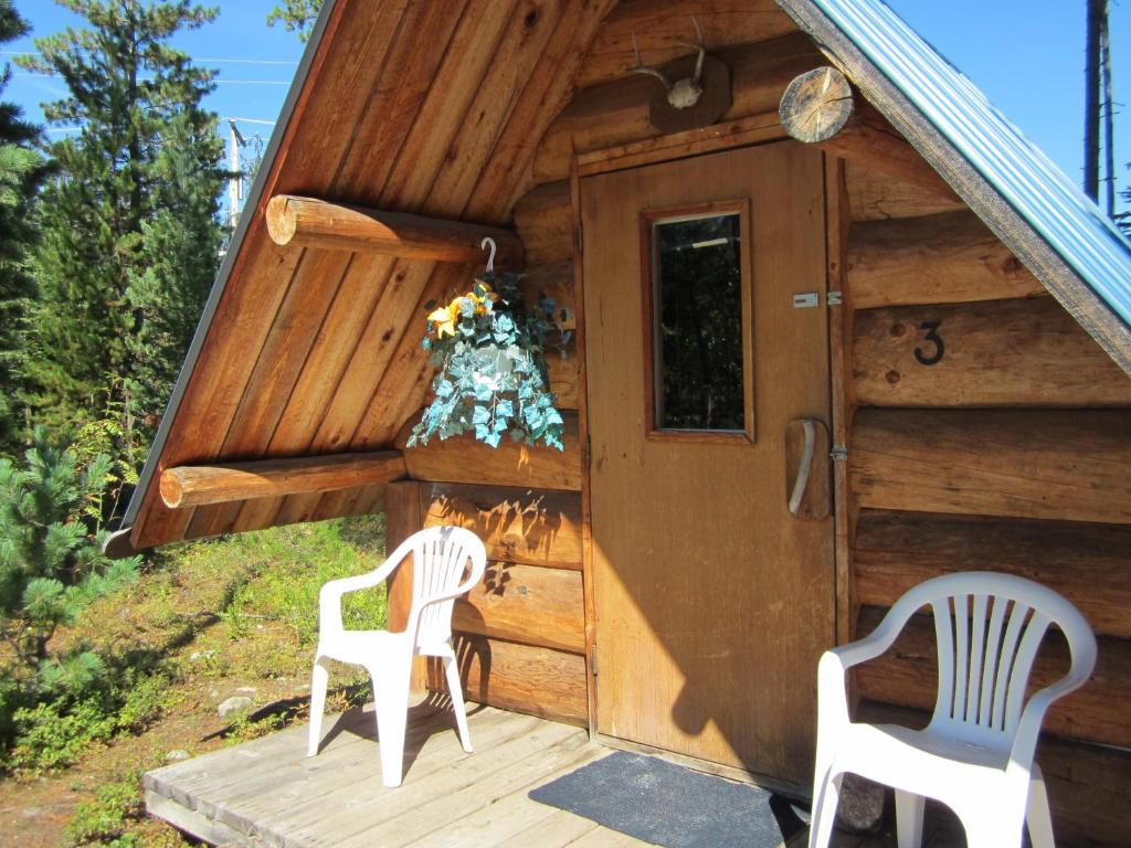 a cabin with two chairs and a door at Blue River Cabins & Campgrounds in Blue River