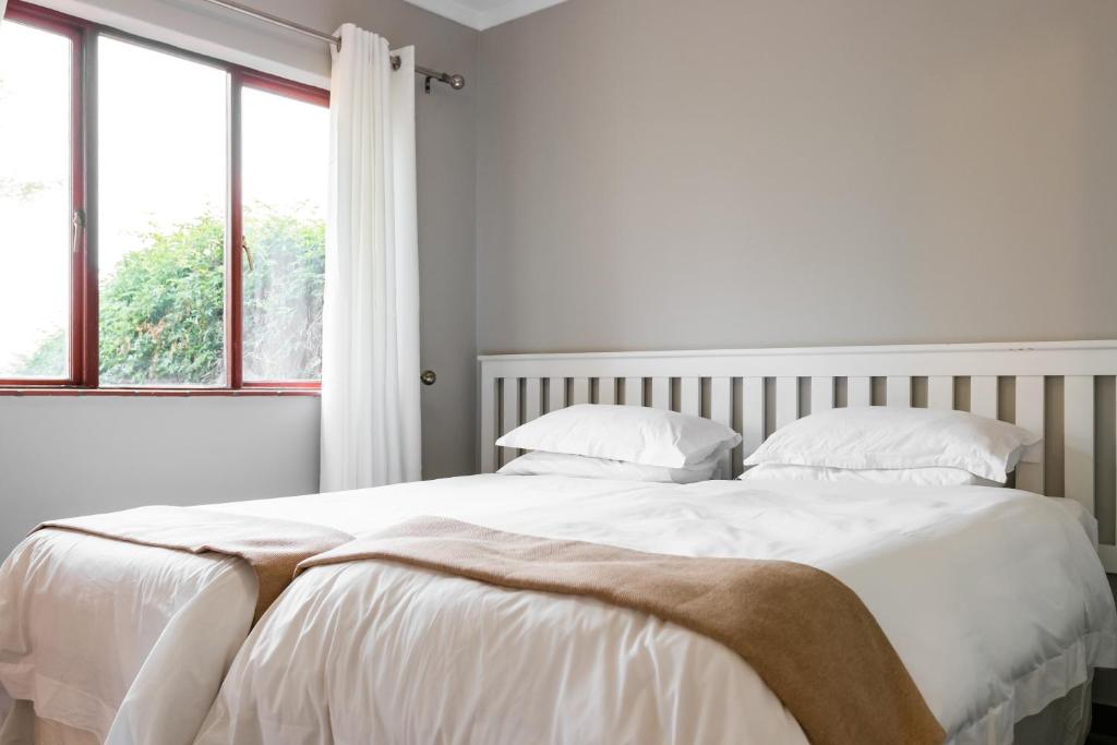 1 dormitorio blanco con 1 cama grande con sábanas y almohadas blancas en Unit 12, Greenway Woods, White River, en Die Winkler