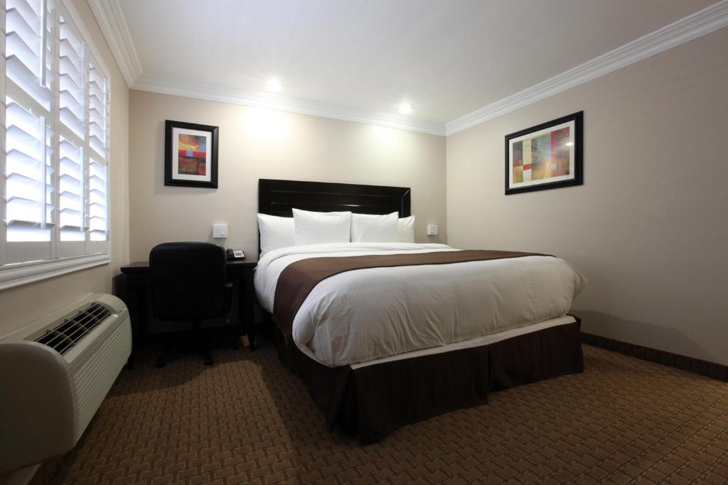 a hotel room with a large bed and a chair at Raincross Hotel Riverside in Riverside