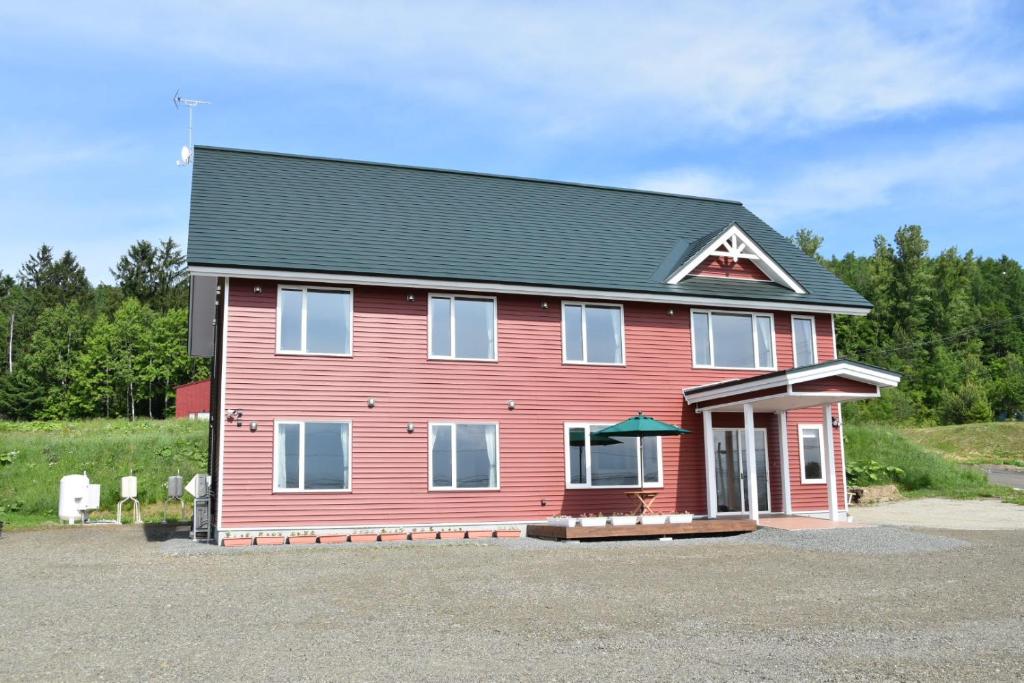 een rood huis met een zwart dak bij Hotel Hanafuji Inn in Furano