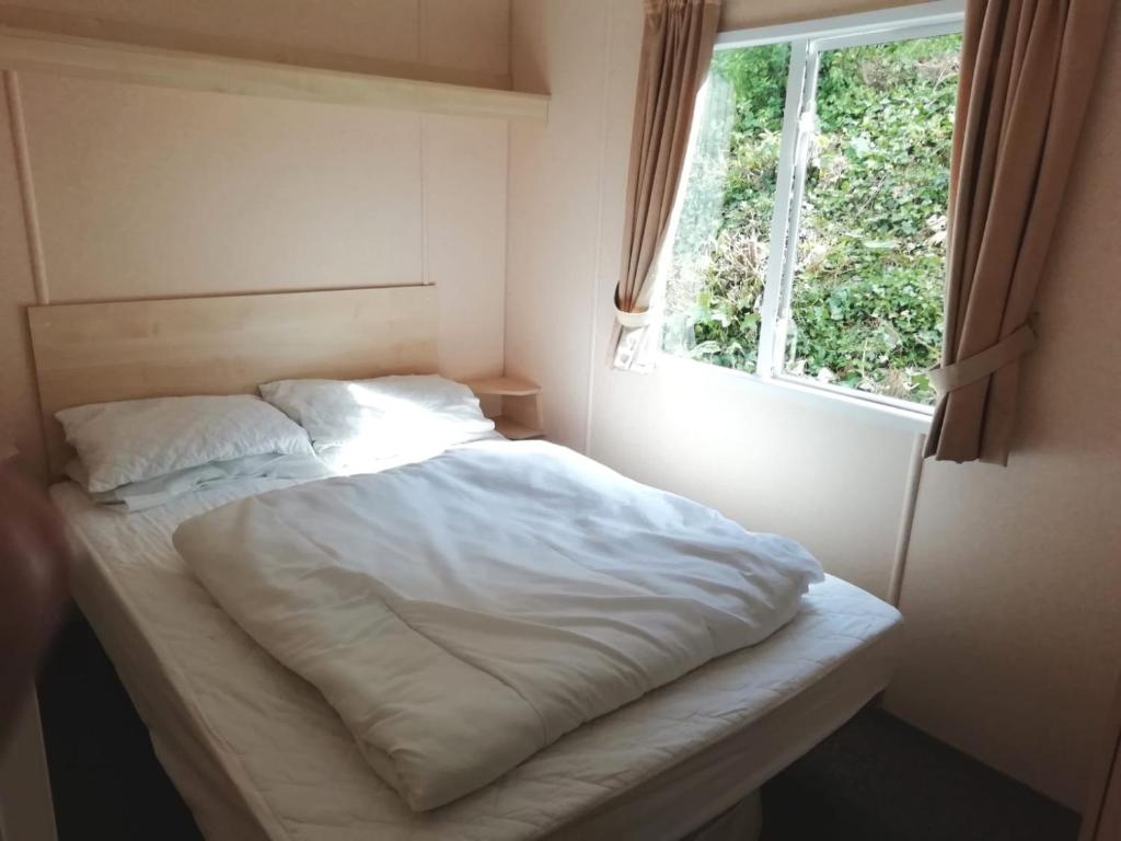 a white bed in a room with a window at Swanage bay caravan in Swanage