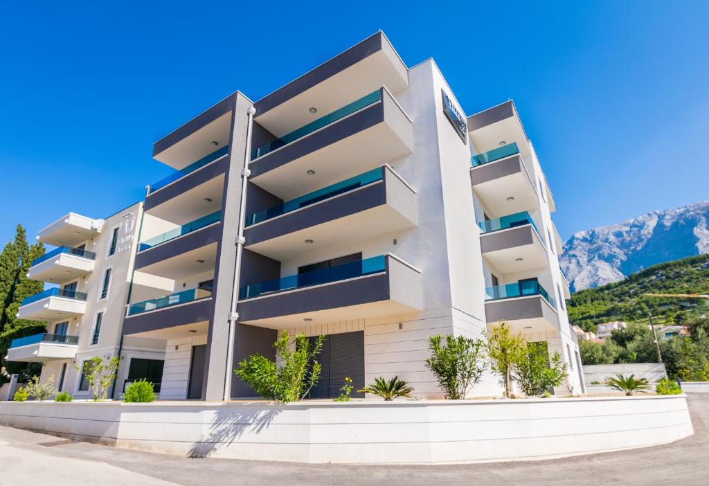 un edificio de apartamentos blanco con montañas en el fondo en Villa Ivo Apartmani, en Promajna