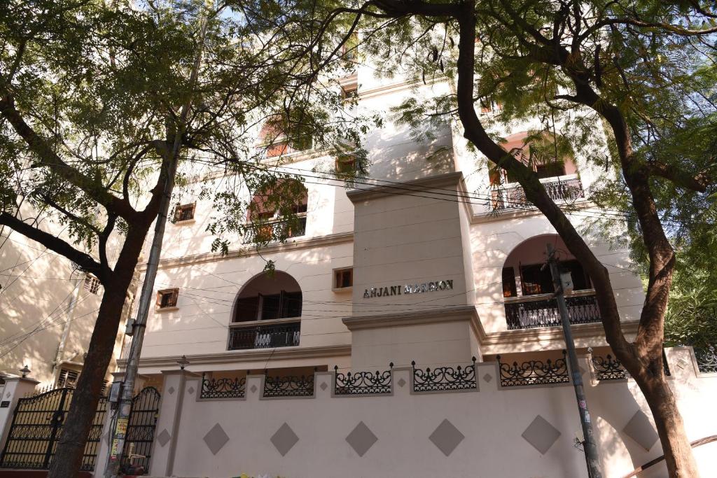 um edifício branco com árvores em frente em anjani mansion em Hyderabad