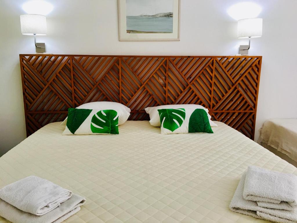 Una cama con dos almohadas verdes y blancas. en Onar studios & residences, en Pisses