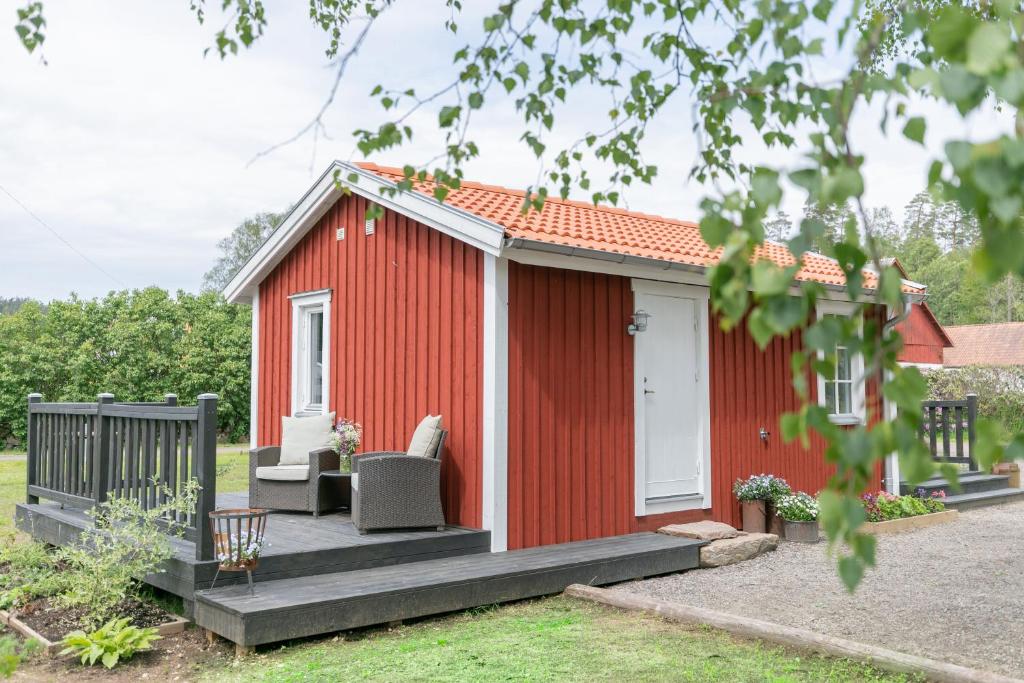 czerwona szopa z gankiem i dwoma krzesłami w obiekcie Gunnagård w mieście Ullared