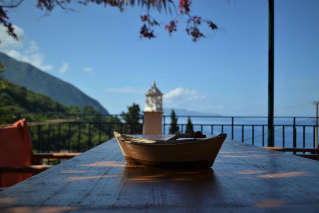 una piccola barca seduta su un tavolo con una torre dell'orologio sullo sfondo di Giannatos Studios- Isabella a Póros