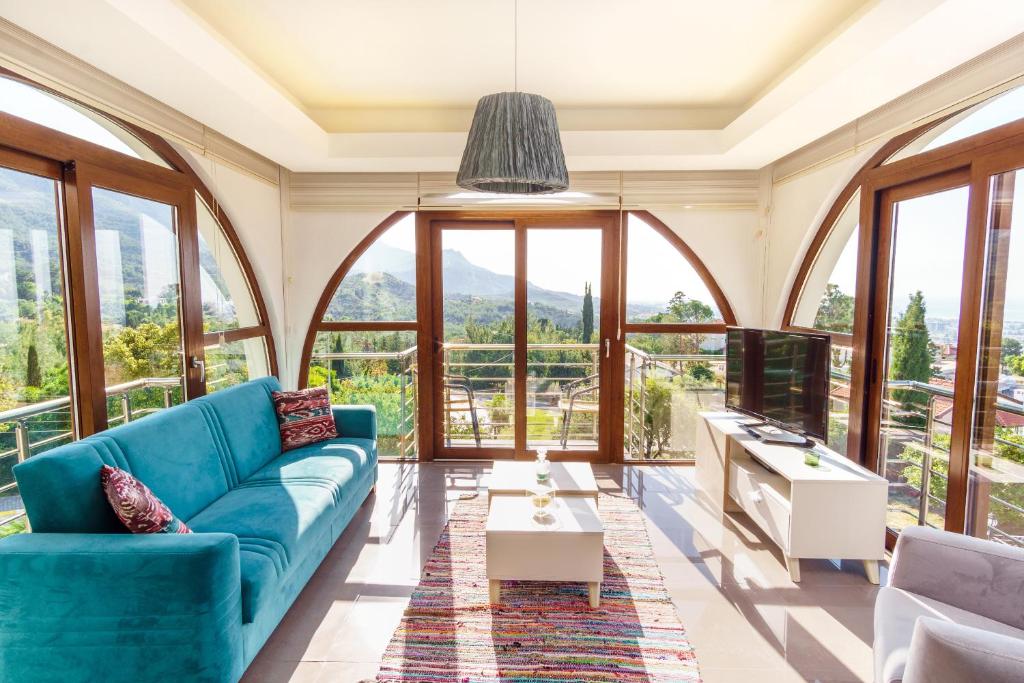 sala de estar con sofá azul y ventanas grandes en Bellapais Apartments en Kyrenia