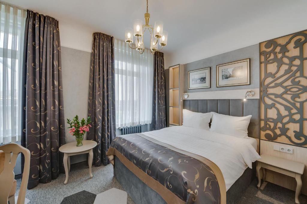 een hotelkamer met een bed en een kroonluchter bij Metropole Hotel by Semarah in Rīga