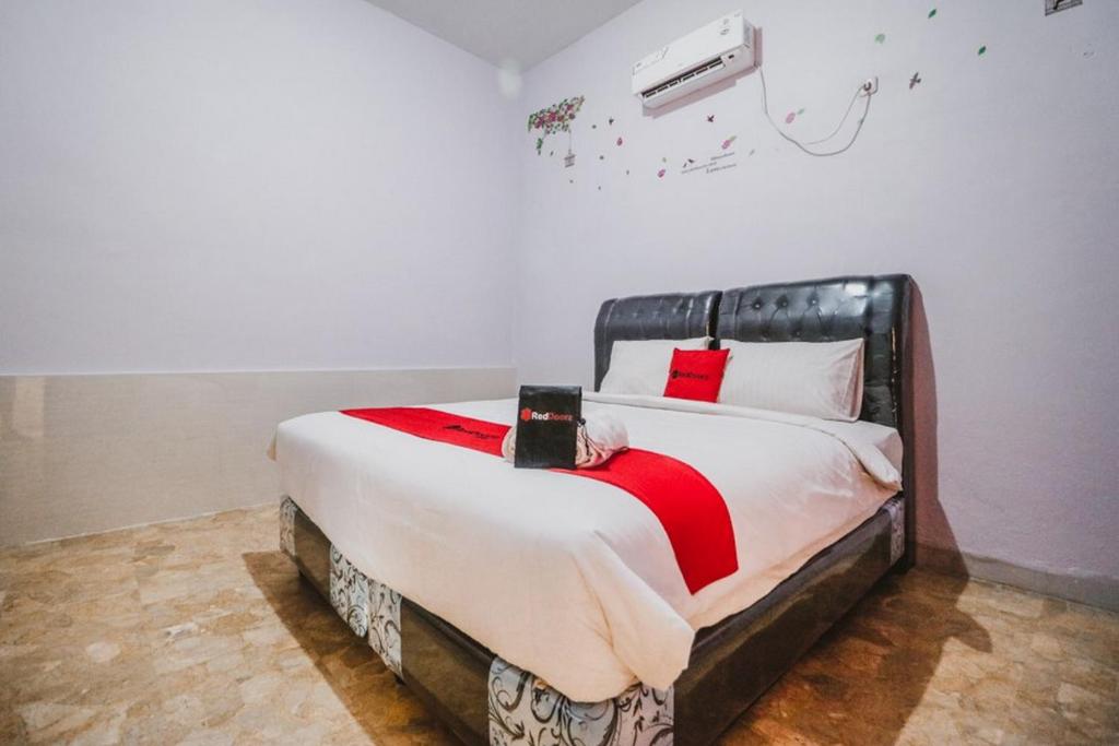 a bedroom with a large bed with a red blanket at RedDoorz near Millennium ICT Center Medan in Medan