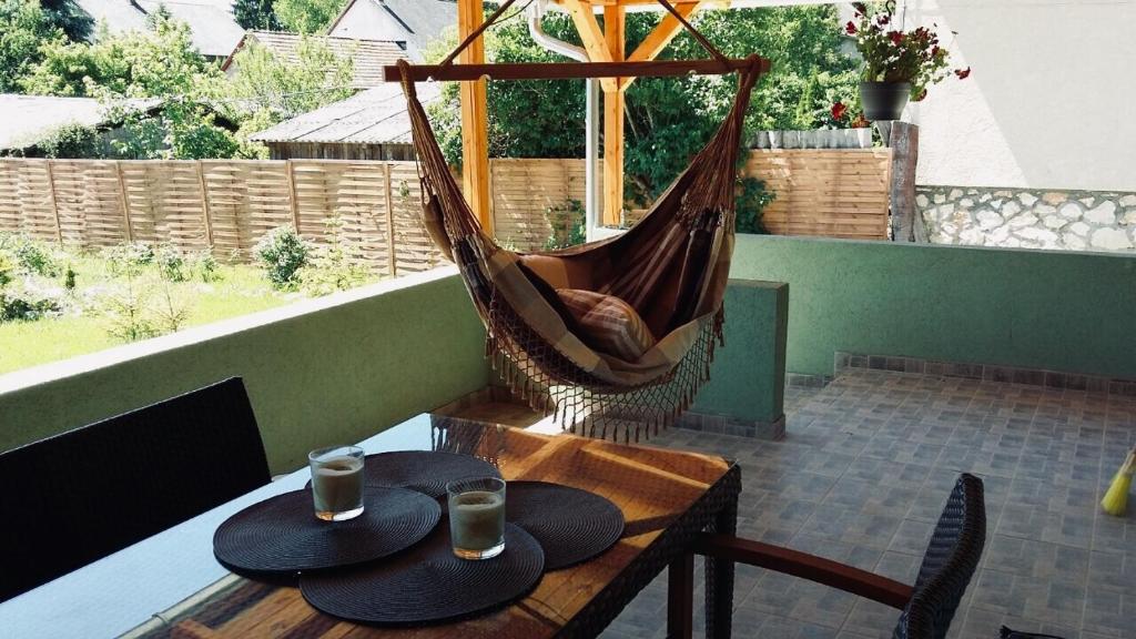 una hamaca en un patio con una mesa con dos sombreros en Bagoli ház en Bakonybél