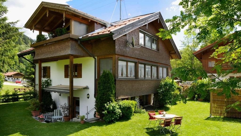 a house with a green yard with a table at Geigers Ferienhaus in Tiefenbach bei Oberstdorf