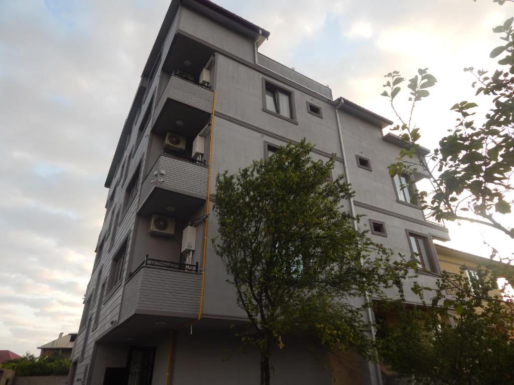 een hoog wit gebouw met balkons en een boom bij MY HOUSE in Batoemi