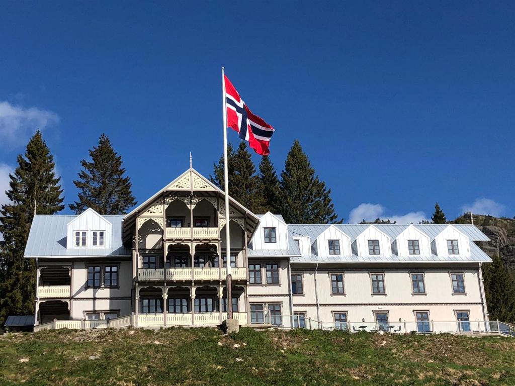 a large white house with a canadian flag on top of it at Hotell Eikerapen Gjestegård Åseral in Åseral