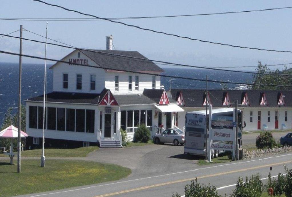a large white building on the side of a road at Hôtel Motel du Rocher in Rivière-la-Madeleine