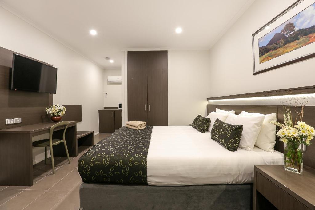 Habitación de hotel con cama y escritorio en Morphettville Motor Inn en Glenelg