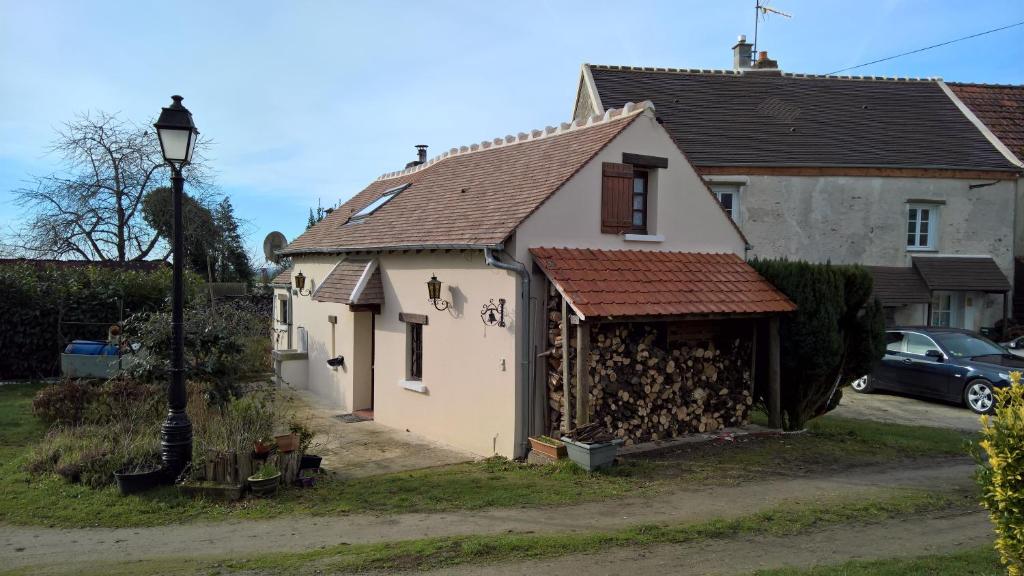 une petite maison blanche avec un toit rouillé dans l'établissement LES GITES DU JARIEL, à Jouy-sur-Morin