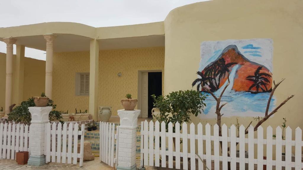 a white picket fence in front of a house with a painting at Villa Atlas Oasis in Shabīkah