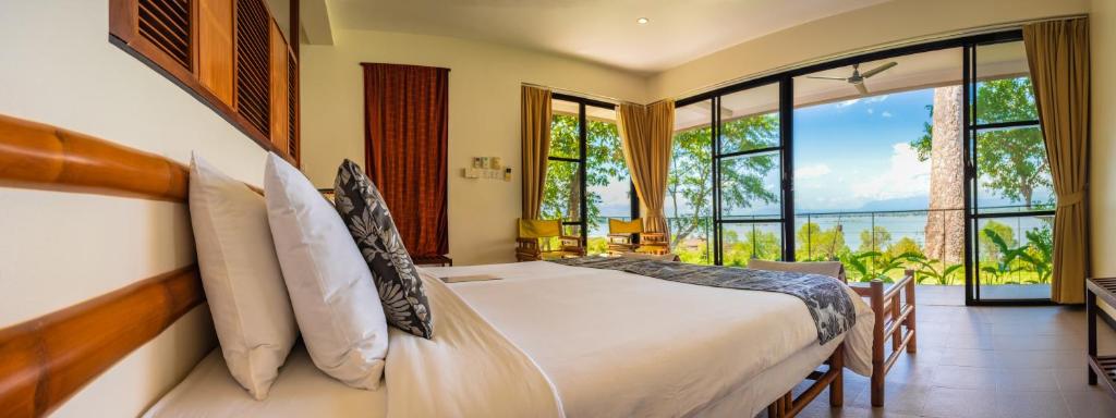 a bedroom with a bed and a large window at The River Resort in Champasak