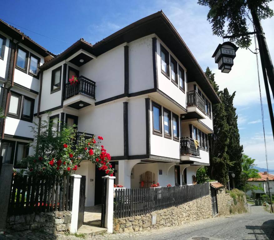a white and black house with red flowers at St. Varvara Apartments in Ohrid