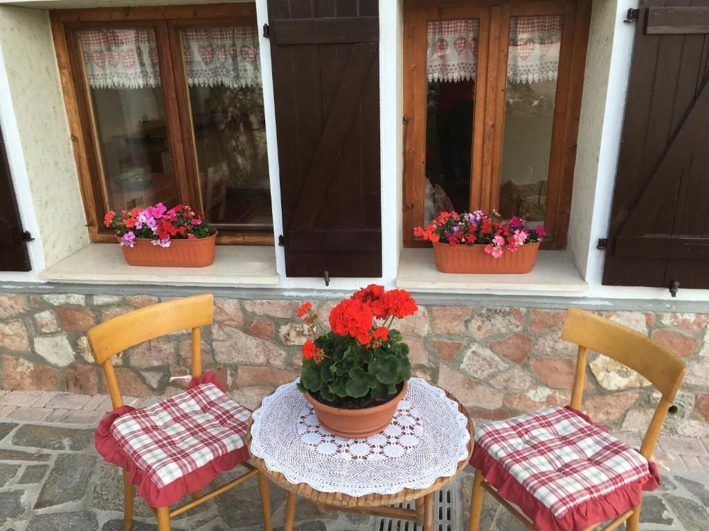 2 chaises et une table avec un pot de fleurs dans l'établissement La casa di Rosy, à Enego
