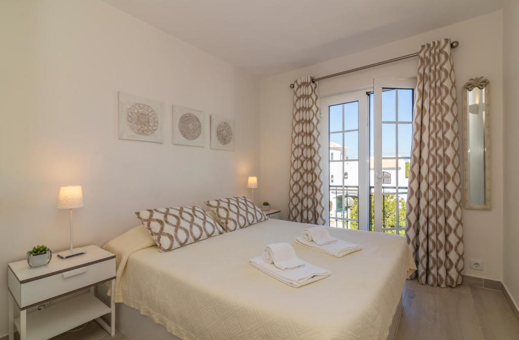 a white bedroom with a bed and a window at The Old Village, Prestige and Solar by Village 4U in Vilamoura