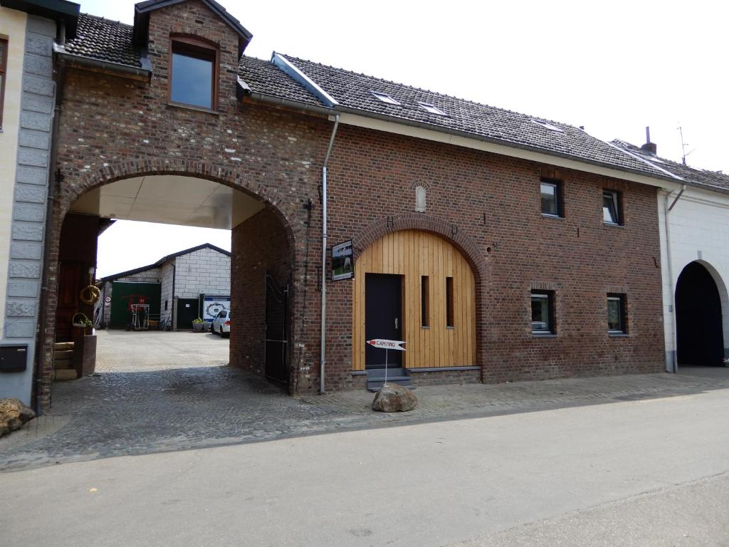 a brick building with an archway next to a street at De Schuur in Walem