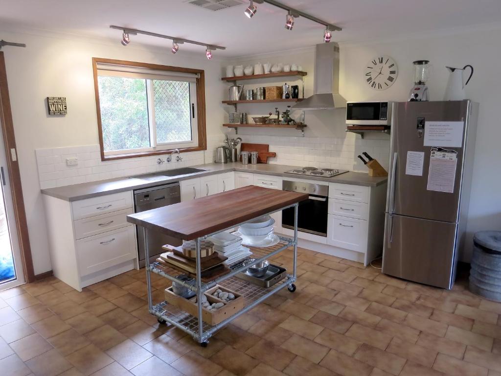 a kitchen with a wooden table and a refrigerator at A2@Port Willy in Port Willunga