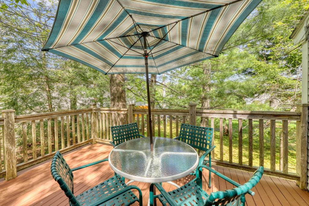 einen Tisch und Stühle auf einer Terrasse mit einem Sonnenschirm in der Unterkunft Quintessential Maine Cottage in Ogunquit