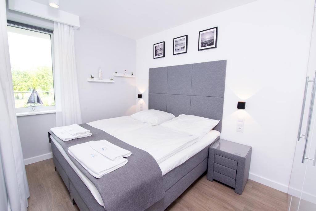 a white bedroom with a large bed and a window at Apartament K&K Klifowa Rewal in Rewal