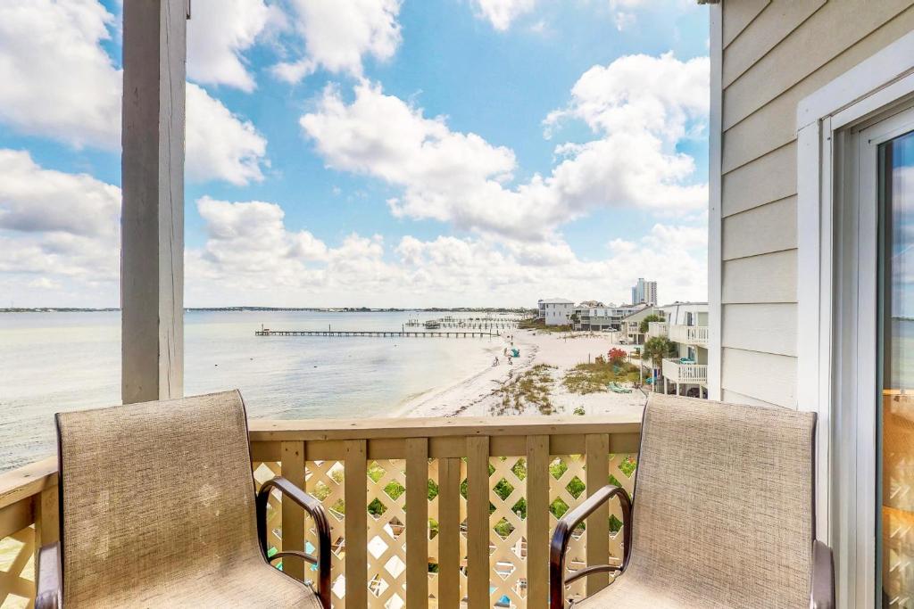 een balkon met 2 stoelen en uitzicht op het strand bij Baywatch in Pensacola Beach