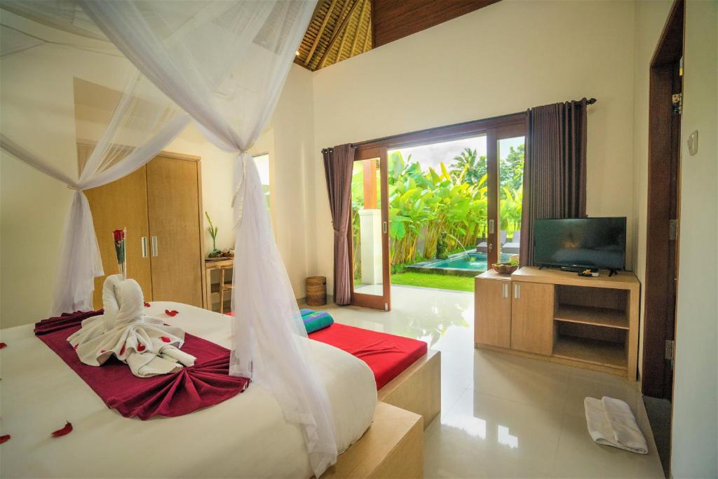 a bedroom with a bed and a tv and a room at Three Gold Luxury Private Villas in Ubud