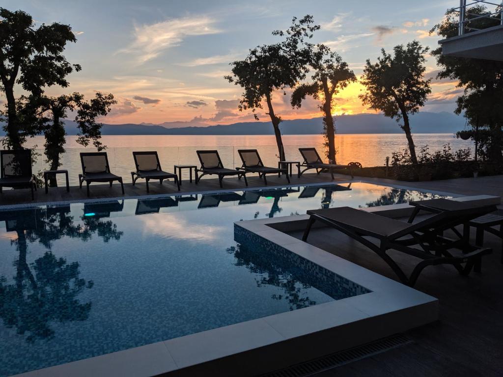 een zwembad met stoelen en een zonsondergang op de achtergrond bij Golden Sunset Apartments in Ohrid