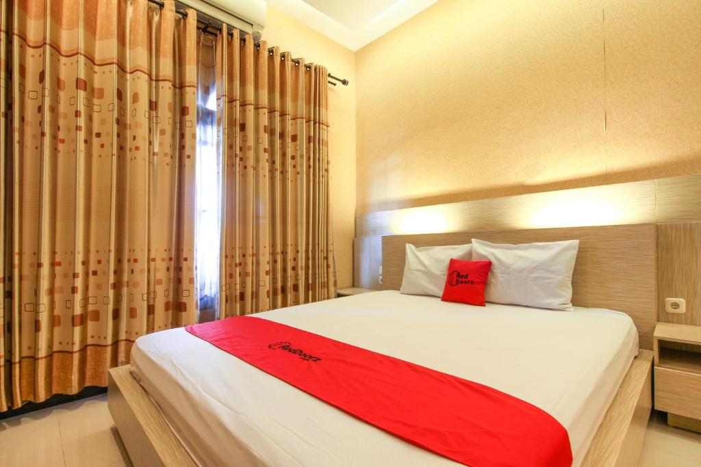 a bedroom with a bed with a red blanket on it at RedDoorz near Candi Ratu Boko in Yogyakarta