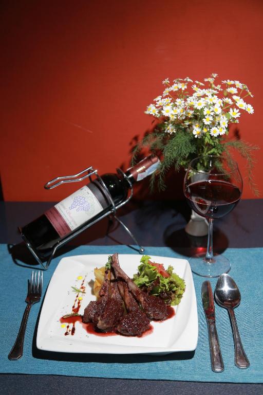 a plate of steak with a bottle of wine and a glass at Shodlik Palace in Tashkent