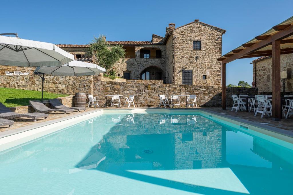 a swimming pool in front of a stone house at La Rimbecca Greve in Chianti in Greve in Chianti