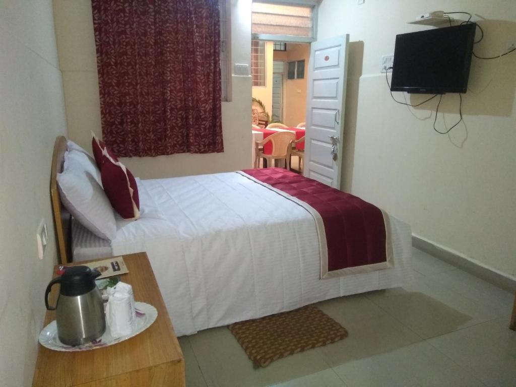 a small bedroom with a bed and a television at KSTDC Hotel Mayura TalaKaveri, Bhagamandala in Madikeri