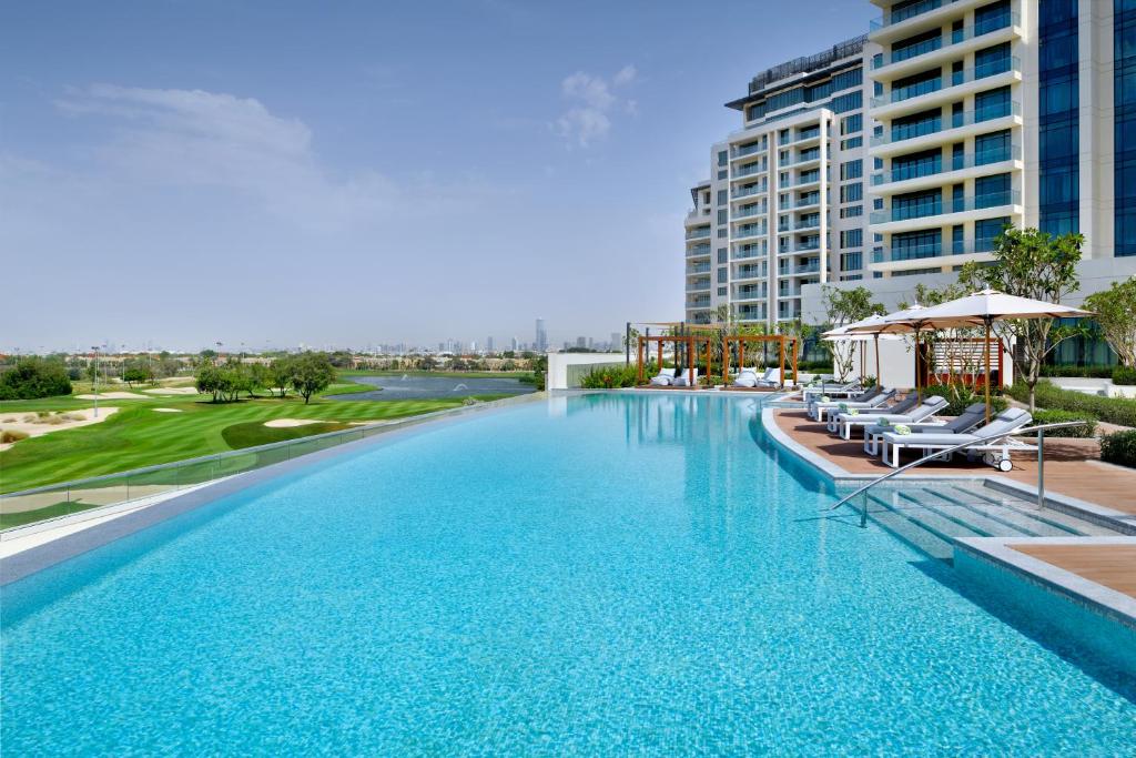 a large swimming pool with chairs and a building at Vida Emirates Hills in Dubai