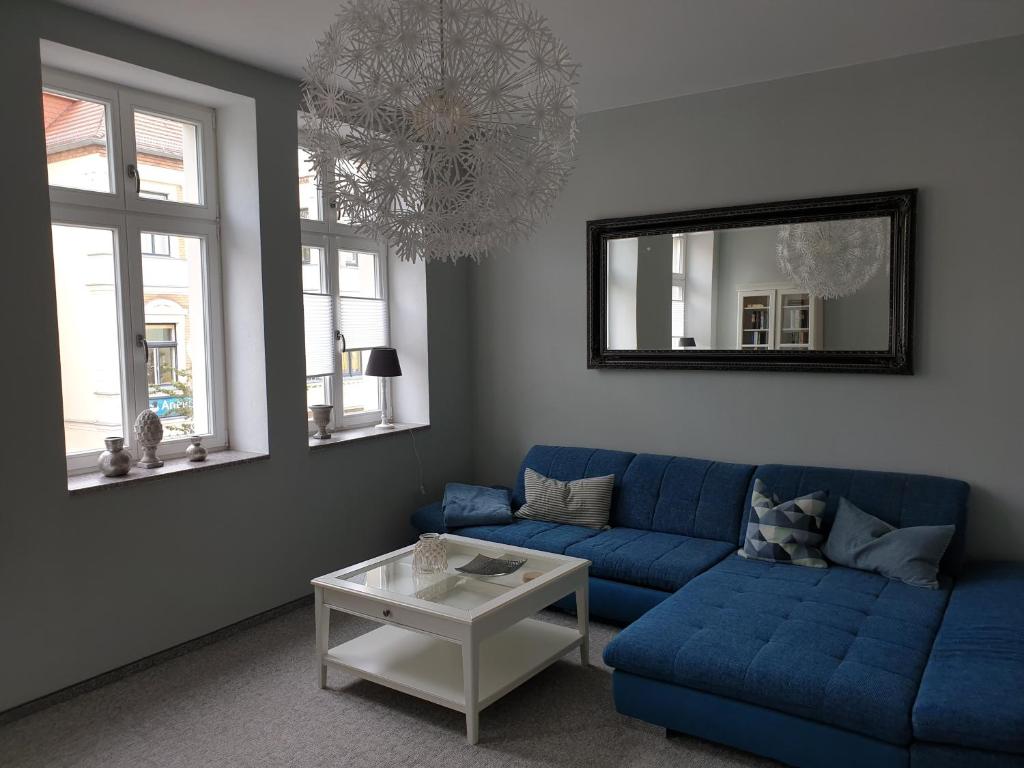 a living room with a blue couch and a mirror at Apartment im Herzen von Neustrelitz in Neustrelitz