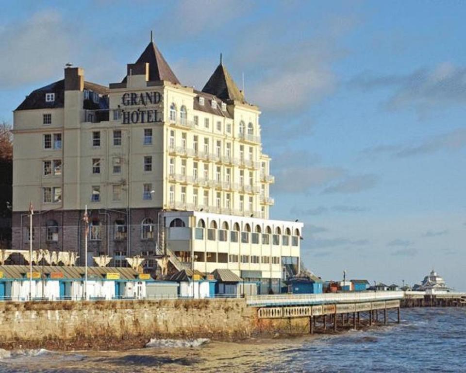 um grande edifício na costa de uma massa de água em The Grand Hotel em Llandudno