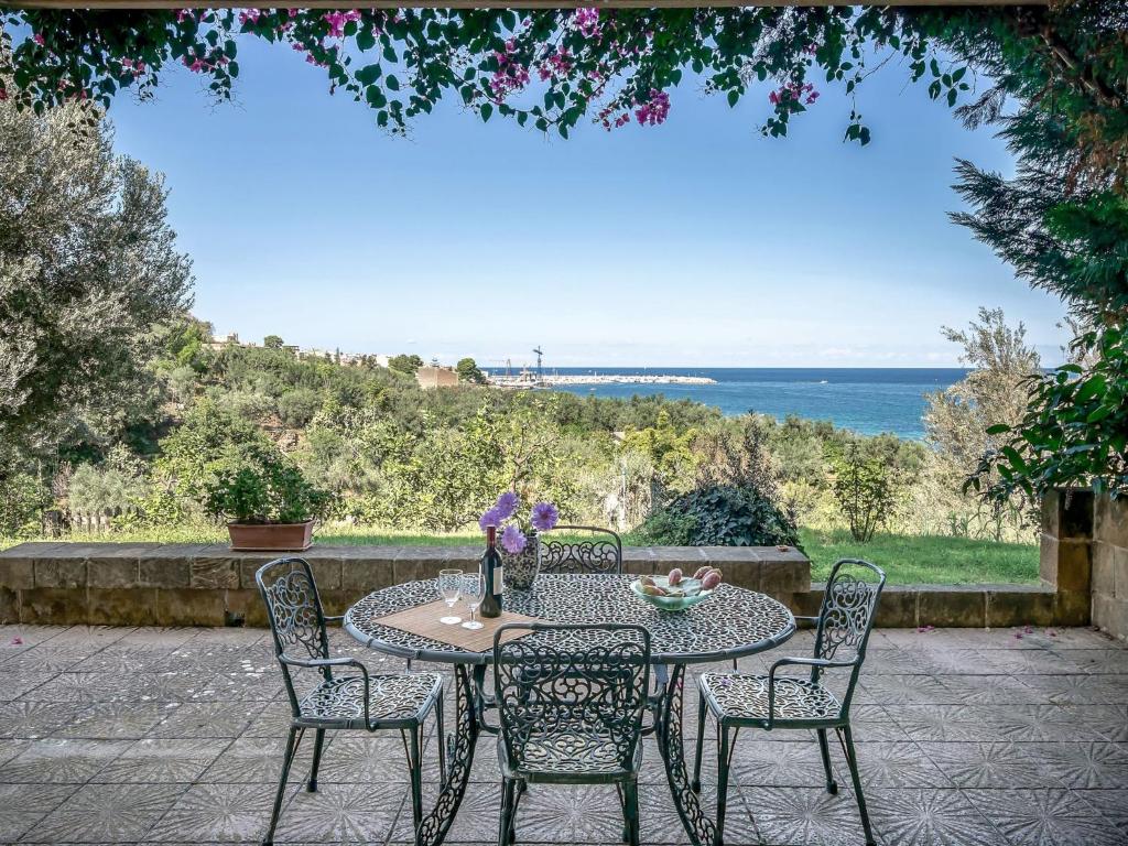 einen Terrassentisch mit Stühlen und einen Tisch mit Blumen darauf in der Unterkunft Apartment Cicladi-2 by Interhome in Santa Flavia