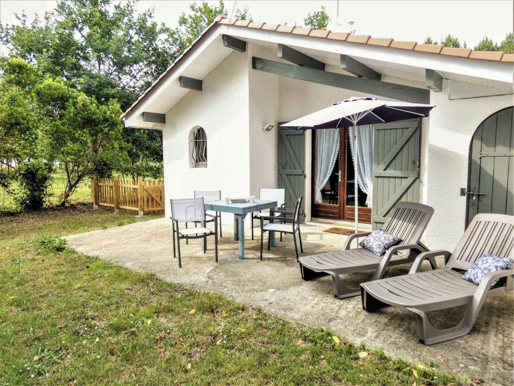 a patio with a table and chairs and an umbrella at Holiday Home Le Fournil by Interhome in Mimizan