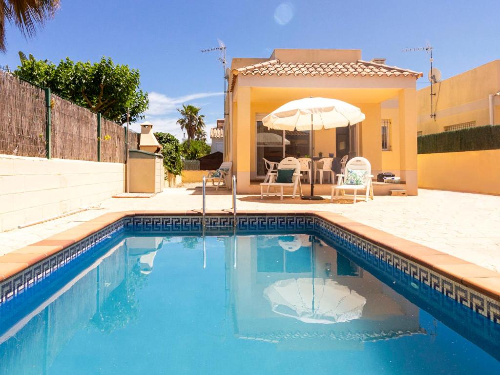 a swimming pool with an umbrella next to a house at Holiday Home 1 Casas by Interhome in Riumar